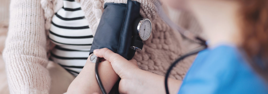 Less worries more positive moments. Close up view on a female nurse sitting in front of a senior patient while measuring her blood pressure during a regular visit.