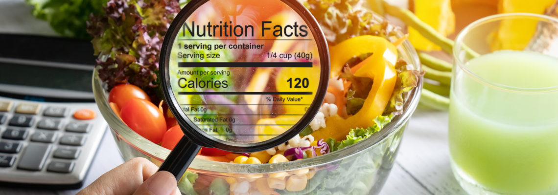 nutritional information concept. hand use the magnifying glass to zoom in to see the details of the nutrition facts from food , salad bowl