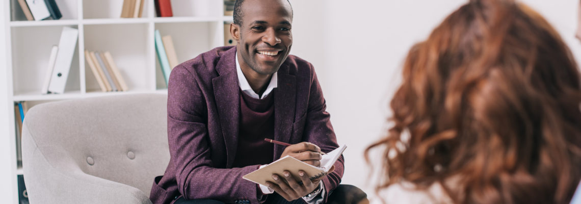 Smiling african american psychiatrist talking to young couple